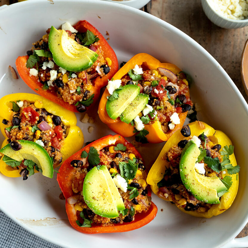 An image of prepared Spicy Stuffed Mexican Peppers made with quinoa, Pacific Foods® Organic Vegetable Broth, Pacific Foods® Organic Cream of Mushroom Condensed Soup, black beans, tomatoes, corn, bell peppers, cilantro, avocado and cotija cheese.